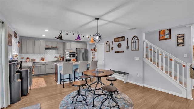 kitchen featuring pendant lighting, light wood-type flooring, a center island, gray cabinetry, and appliances with stainless steel finishes