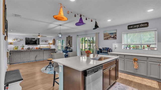 kitchen with stainless steel dishwasher, a kitchen island with sink, sink, and a wealth of natural light