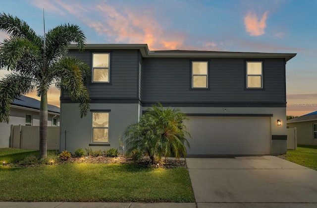 view of front facade with stucco siding, a front lawn, driveway, fence, and a garage