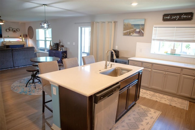 kitchen with open floor plan, dishwasher, a breakfast bar, light wood-style floors, and a sink