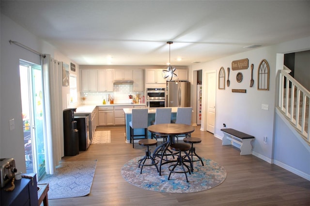 dining area with visible vents, stairway, wood finished floors, and baseboards