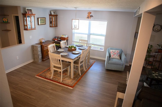 dining area with baseboards, a textured ceiling, and wood finished floors