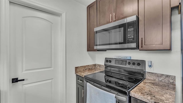 kitchen featuring light stone countertops, stainless steel appliances, and dark brown cabinets