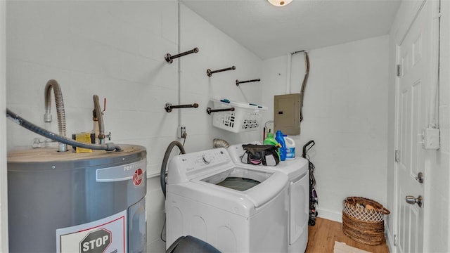 clothes washing area featuring water heater, washing machine and clothes dryer, electric panel, a textured ceiling, and light hardwood / wood-style floors