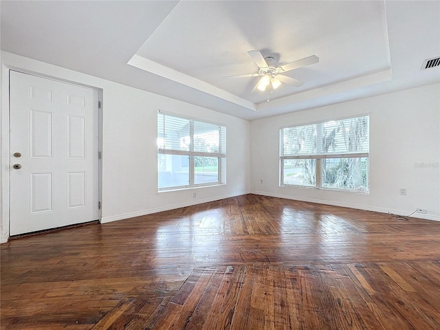 unfurnished room with ceiling fan, a raised ceiling, and dark hardwood / wood-style floors