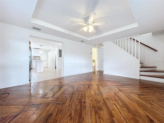 unfurnished living room featuring ceiling fan and a tray ceiling