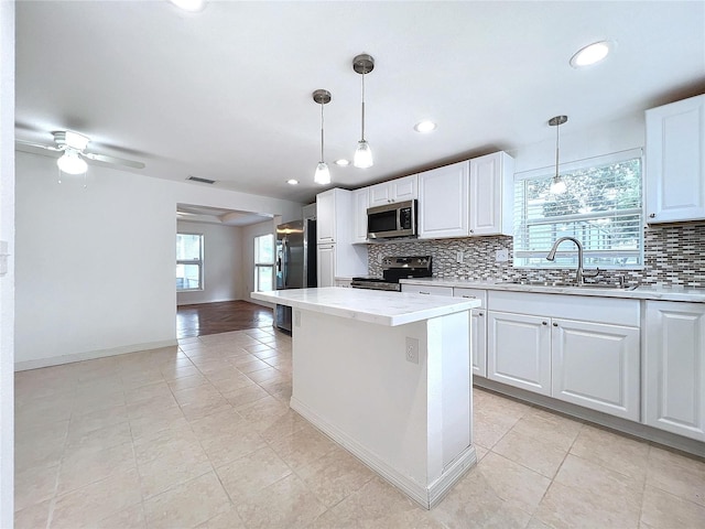 kitchen with white cabinets, appliances with stainless steel finishes, sink, and decorative light fixtures