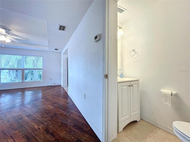 interior space with vanity, hardwood / wood-style flooring, toilet, and ceiling fan