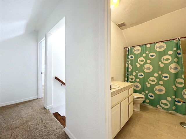 bathroom with tile patterned flooring, vanity, toilet, and vaulted ceiling