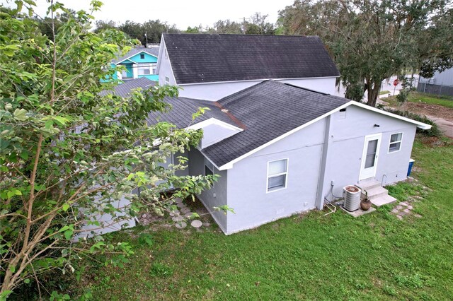 back of house featuring central air condition unit and a yard