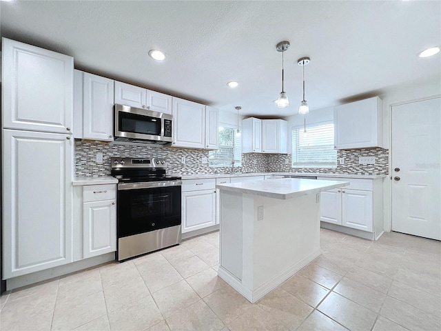 kitchen featuring stainless steel appliances, white cabinets, decorative light fixtures, and a kitchen island