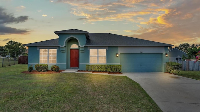 single story home with a garage and a yard