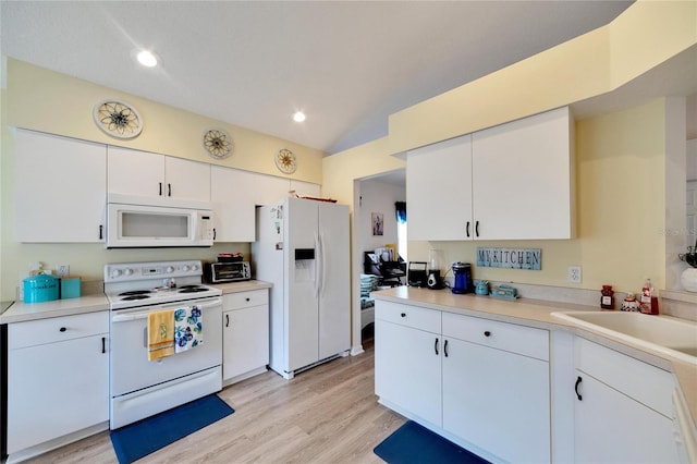 kitchen with lofted ceiling, white appliances, light hardwood / wood-style floors, and white cabinets