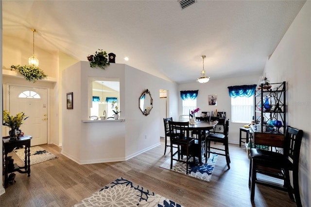 dining space featuring hardwood / wood-style floors, a notable chandelier, and vaulted ceiling