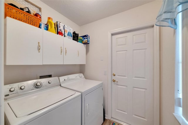 laundry room with separate washer and dryer, cabinets, and a textured ceiling