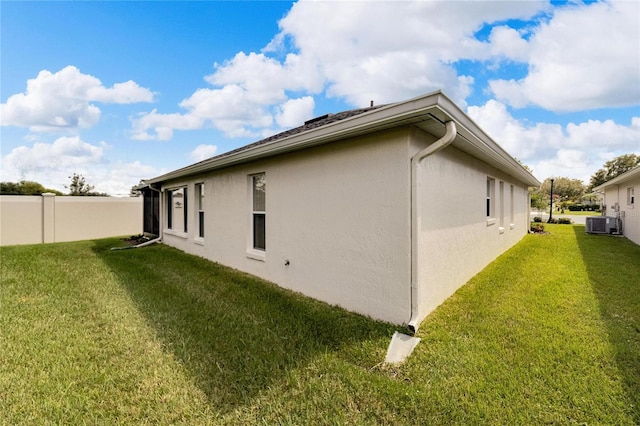 view of property exterior with central AC unit and a yard