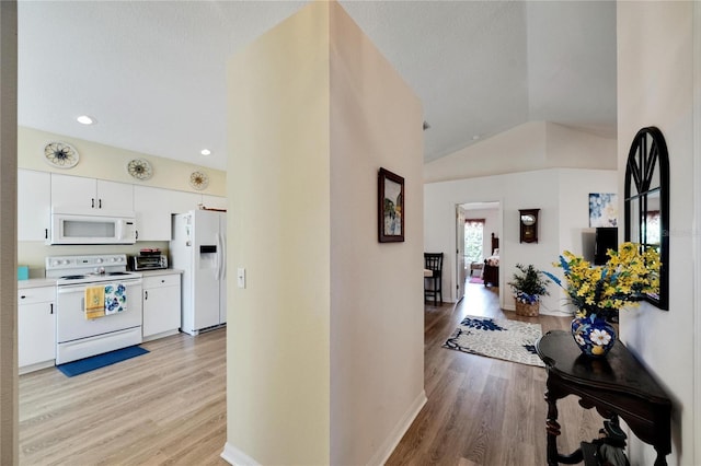 hallway with vaulted ceiling, a textured ceiling, and light wood-type flooring