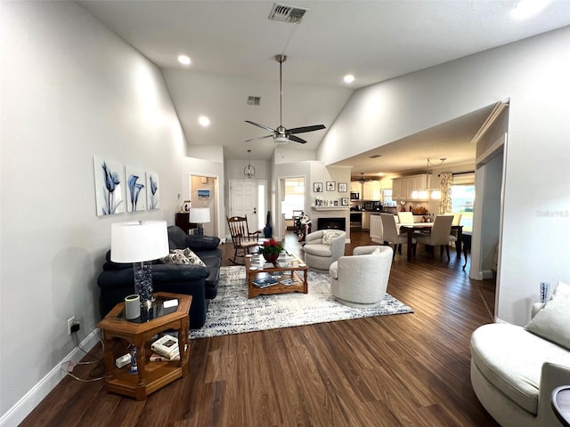 living room with ceiling fan with notable chandelier, dark hardwood / wood-style flooring, and high vaulted ceiling