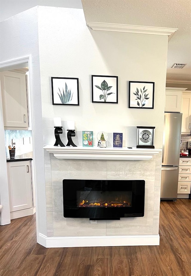 interior details featuring tasteful backsplash, stainless steel fridge, a textured ceiling, hardwood / wood-style flooring, and ornamental molding