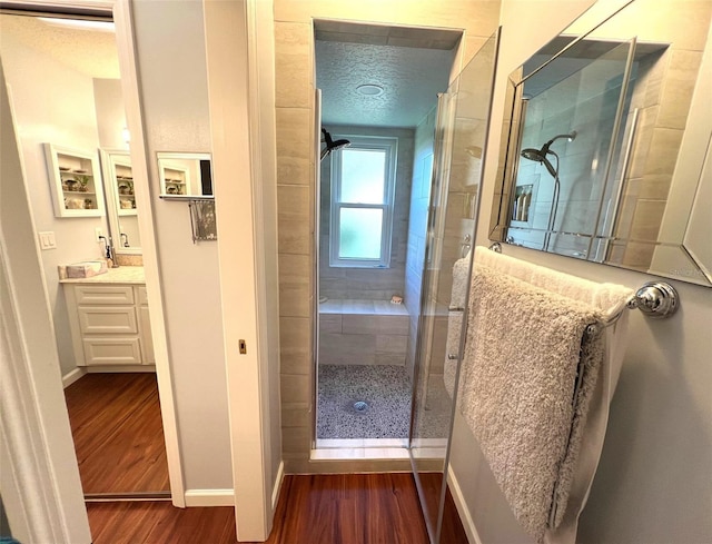 bathroom featuring vanity, hardwood / wood-style floors, a textured ceiling, and an enclosed shower