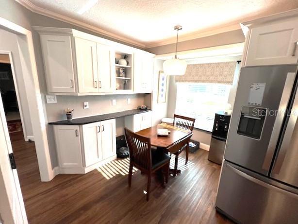 kitchen featuring pendant lighting, white cabinets, ornamental molding, dark hardwood / wood-style flooring, and stainless steel fridge with ice dispenser