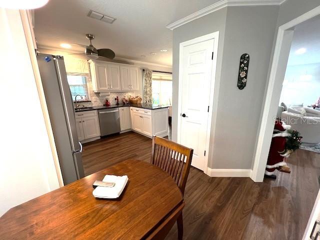 dining space featuring dark hardwood / wood-style flooring, ceiling fan, crown molding, and sink