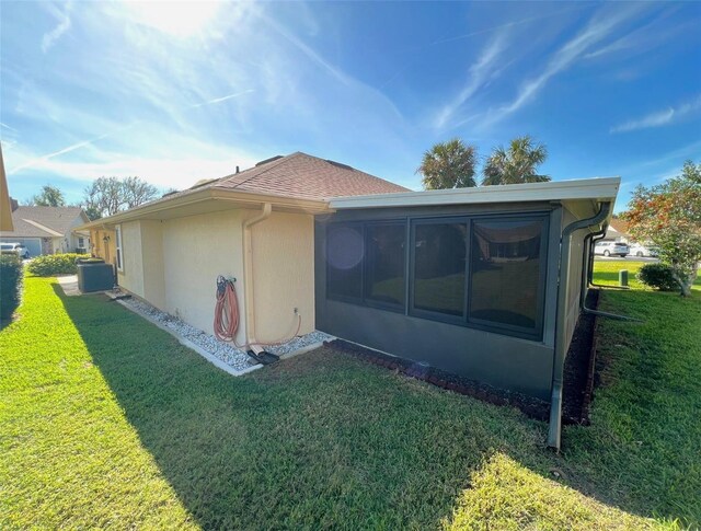 rear view of property featuring central AC, a sunroom, and a yard