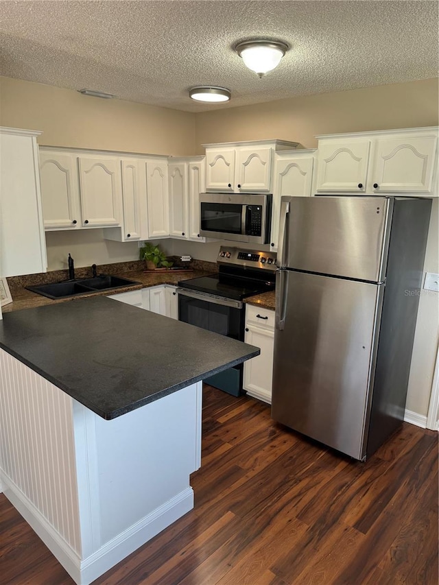 kitchen featuring white cabinets, kitchen peninsula, stainless steel appliances, and a textured ceiling