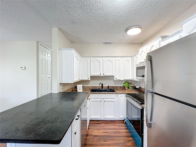 kitchen with white cabinetry, kitchen peninsula, stainless steel appliances, dark wood-type flooring, and sink