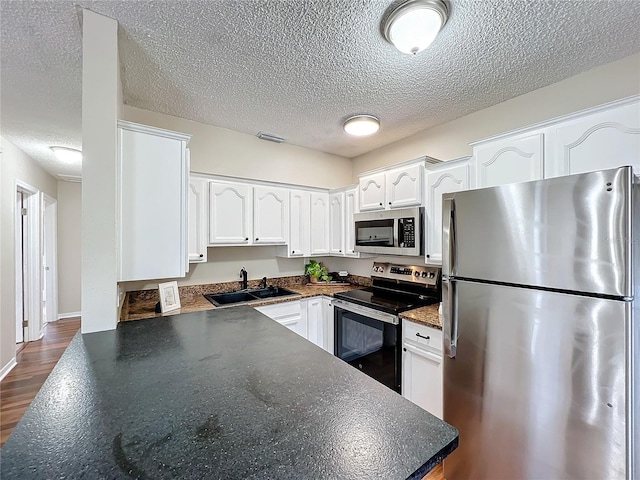 kitchen featuring appliances with stainless steel finishes, sink, dark hardwood / wood-style flooring, and white cabinetry