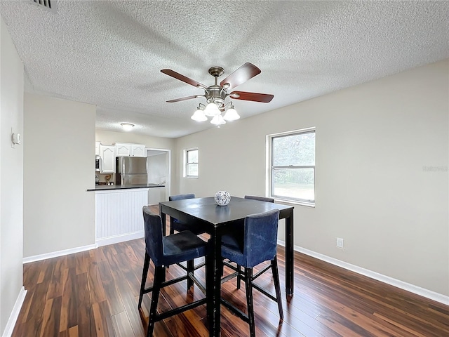 dining area featuring ceiling fan, dark wood-type flooring, and a textured ceiling