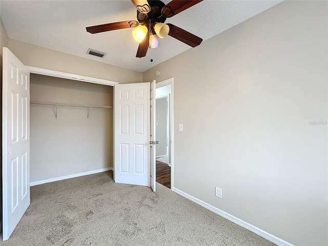 unfurnished bedroom featuring ceiling fan, a textured ceiling, a closet, and carpet flooring