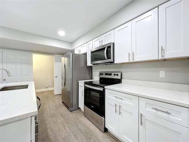 kitchen featuring white cabinets, stainless steel appliances, light stone countertops, and sink