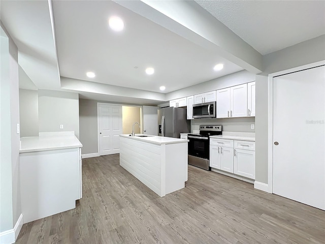 kitchen featuring white cabinets, a center island with sink, sink, light hardwood / wood-style flooring, and stainless steel appliances