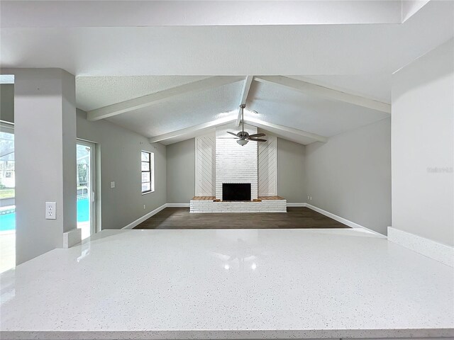 unfurnished living room featuring ceiling fan, lofted ceiling with beams, and a brick fireplace