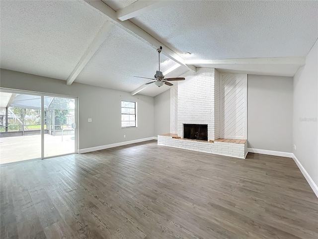 unfurnished living room featuring lofted ceiling with beams, a brick fireplace, ceiling fan, a textured ceiling, and dark hardwood / wood-style flooring