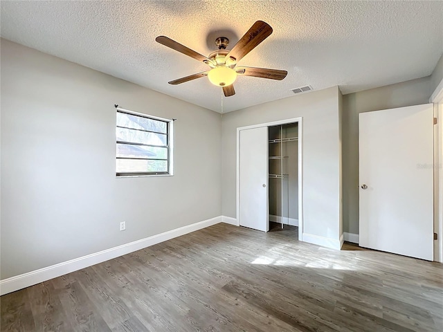 unfurnished bedroom featuring wood-type flooring, a textured ceiling, a closet, and ceiling fan