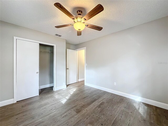 unfurnished bedroom with a closet, a textured ceiling, hardwood / wood-style flooring, and ceiling fan