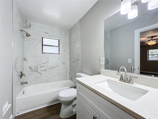 full bathroom with vanity, ceiling fan, hardwood / wood-style floors, toilet, and tiled shower / bath