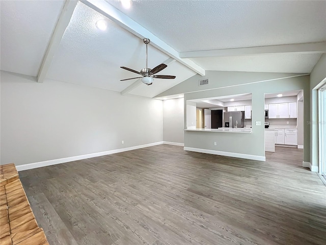 unfurnished living room featuring lofted ceiling with beams, ceiling fan, dark hardwood / wood-style flooring, and a textured ceiling