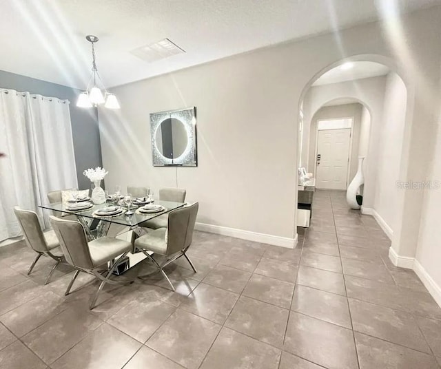 tiled dining room with an inviting chandelier