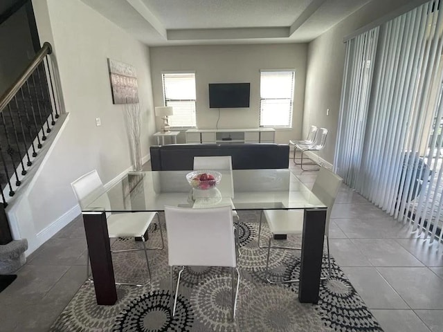 dining space featuring a tray ceiling and tile patterned floors