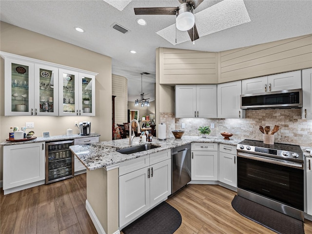 kitchen featuring white cabinetry, kitchen peninsula, stainless steel appliances, wine cooler, and sink