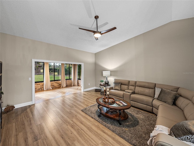 living room with vaulted ceiling, ceiling fan, a textured ceiling, and light wood-type flooring