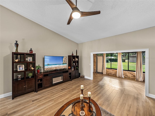 living room with vaulted ceiling, ceiling fan, a textured ceiling, and light hardwood / wood-style floors