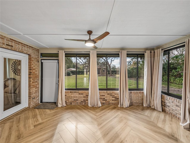 unfurnished sunroom with ceiling fan