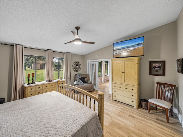 bedroom with ceiling fan, light hardwood / wood-style floors, a textured ceiling, and lofted ceiling