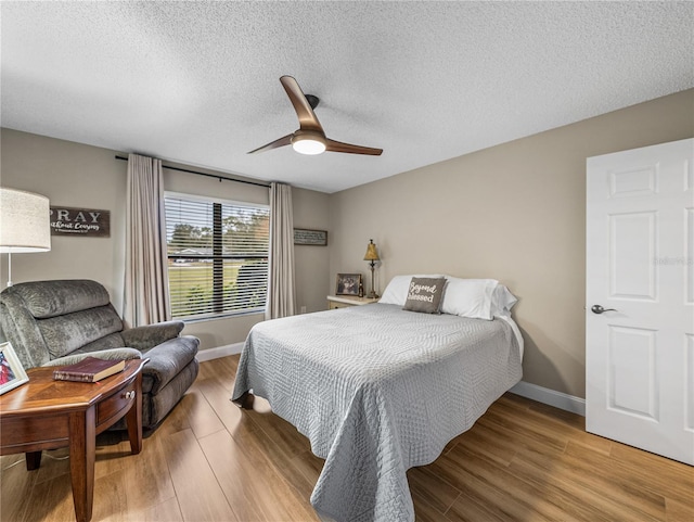 bedroom with ceiling fan, a textured ceiling, and hardwood / wood-style flooring