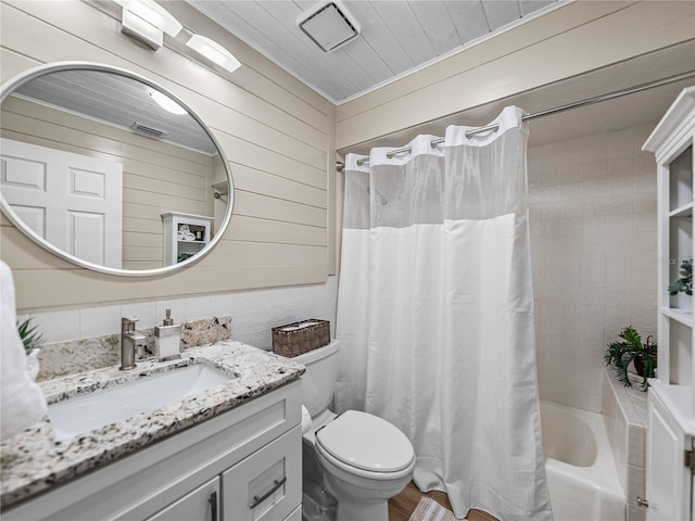 full bathroom featuring toilet, vanity, wood walls, and shower / tub combo with curtain