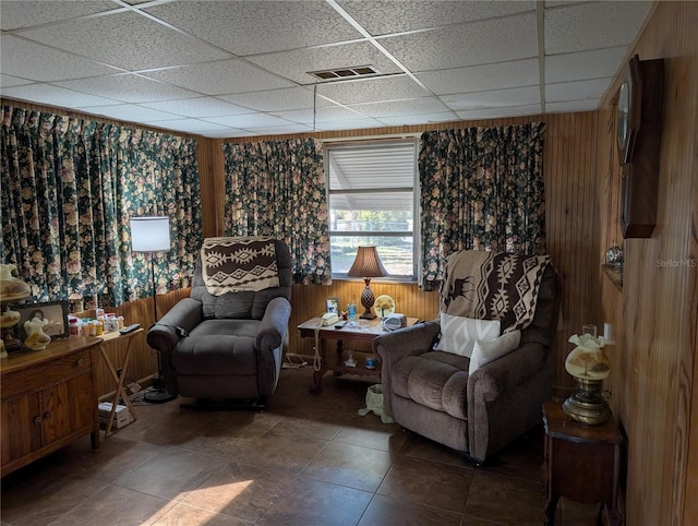 sitting room with a drop ceiling and wood walls